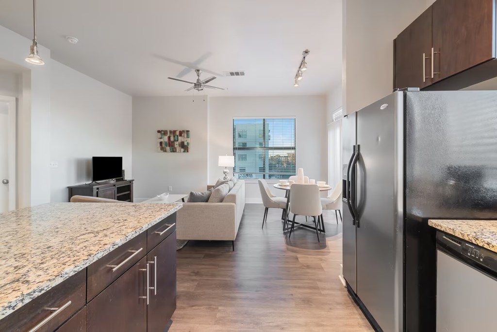 A modern kitchen with granite countertops and a refrigerator.
